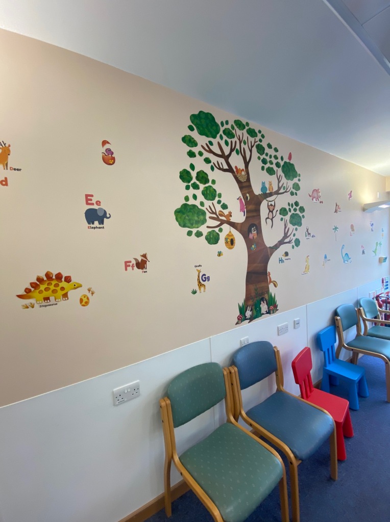 Example of the wall art in the waiting area which include a big tree with animals